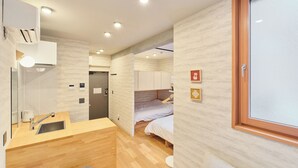 Quarto de hotel compacto com cozinha compacta, uma cama e banheiro.
