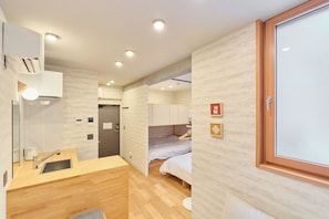 A compact hotel room with a kitchenette, a bed, and a bathroom. - Tomori (Shinjuku-ku)