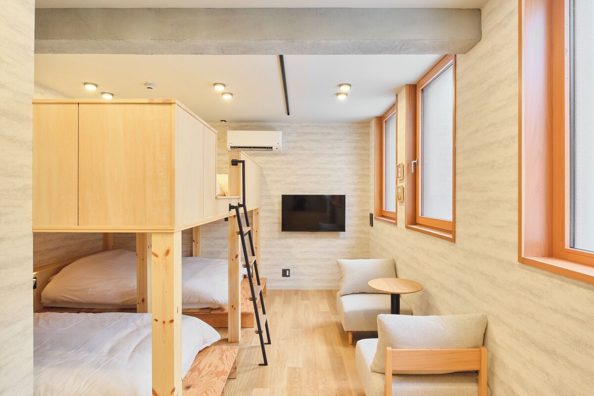 A compact room with bunk beds, a flat-screen TV, a small round table, and a window.