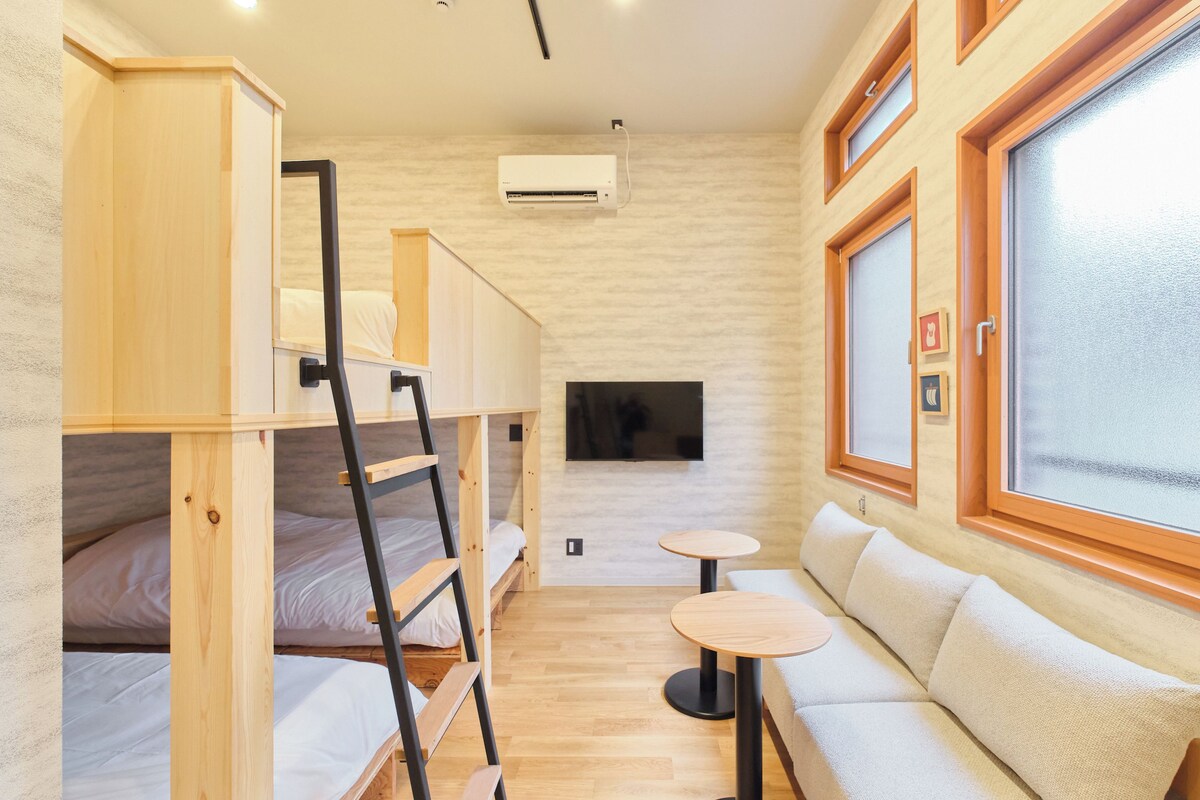 A compact room with bunk beds, a sofa, a small table, and a TV.