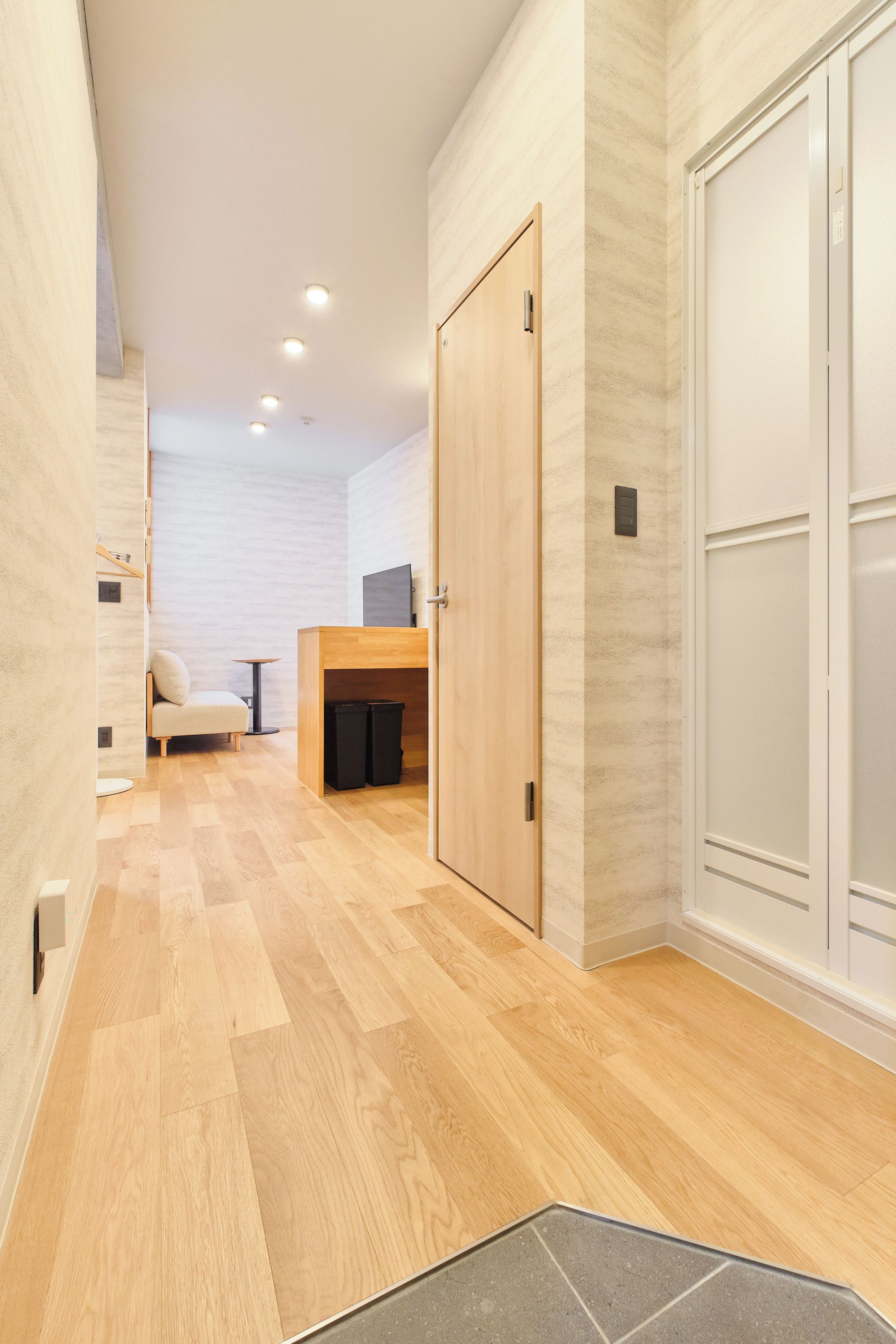 A hallway with wooden flooring, a sofa, a small table, and a TV on a stand.