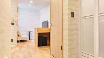 A hallway with wooden flooring, a sofa, a small table, and a TV on a stand.
