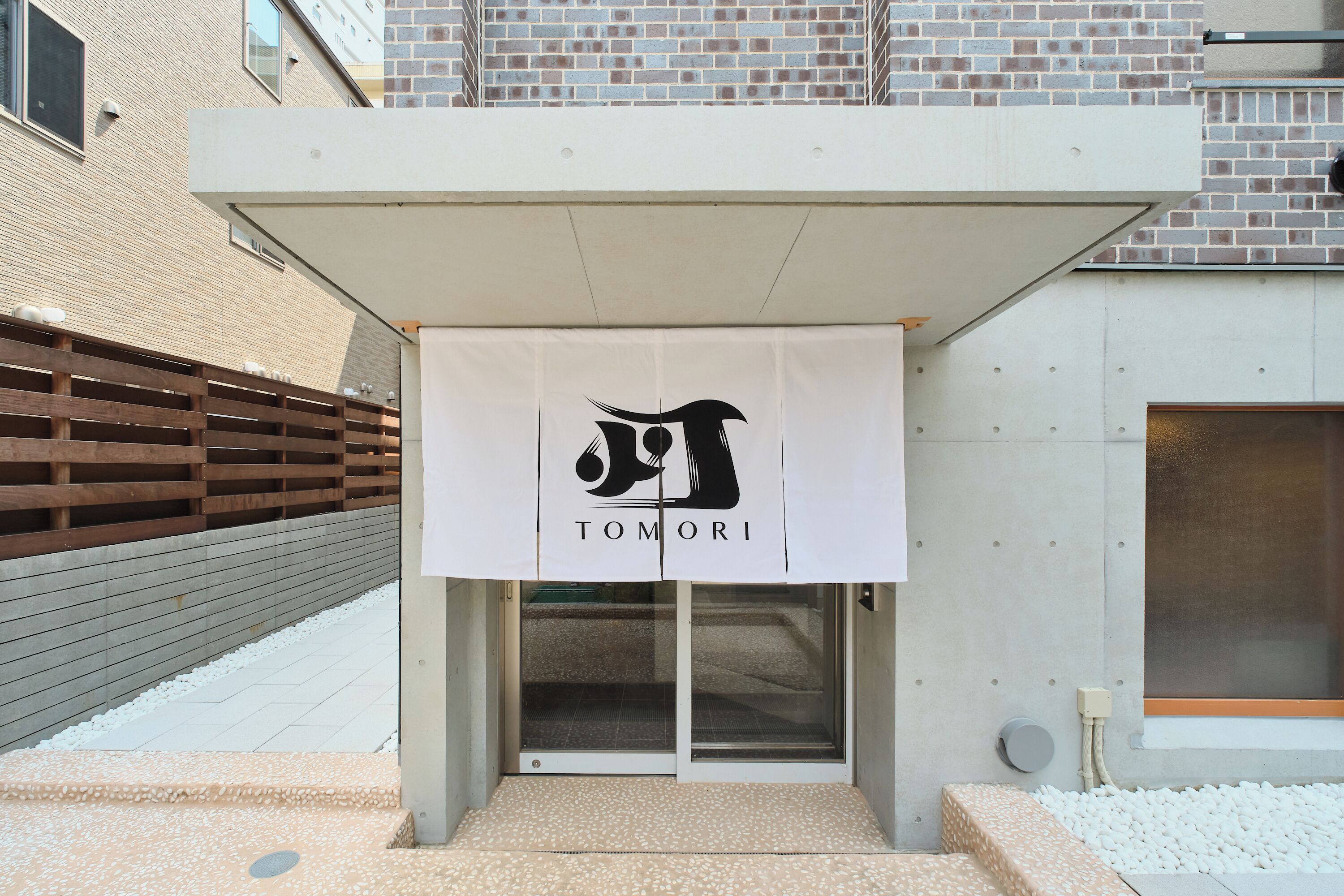 A building entrance with a banner displaying the name 'TOMORI'.