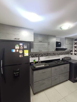 A modern kitchen with a refrigerator, stove, sink, and grey cabinets. - Hermoso apartamento amoblado en Meléndez City 403 (Cali)