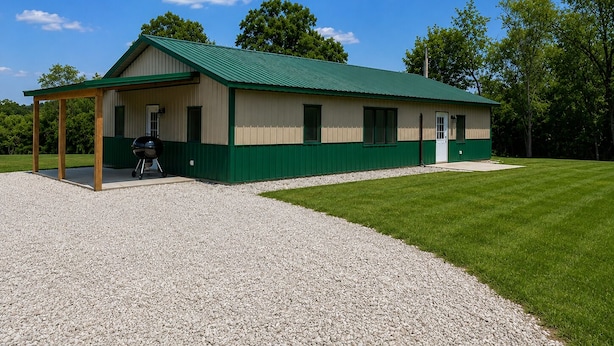A single-story building with a green roof and beige walls, featuring a covered outdoor area with a barbecue grill. - Rustic Cabin Escape in Welcoming Brown County. Reconnect, Relax & Unwind (Mount Sterling)