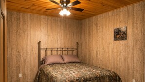 A bedroom with a wooden ceiling, a bed with camouflage bedding, a ceiling fan, and a small picture on the wall. - Rustic Cabin Escape in Welcoming Brown County. Reconnect, Relax & Unwind (Mount Sterling)