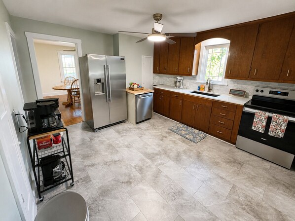 A kitchen with a refrigerator, dishwasher, oven, and wooden cabinets.