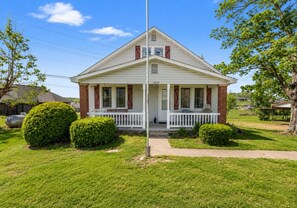 Een gelijkvloers huis met een veranda, een brievenbus en een heldere lucht.