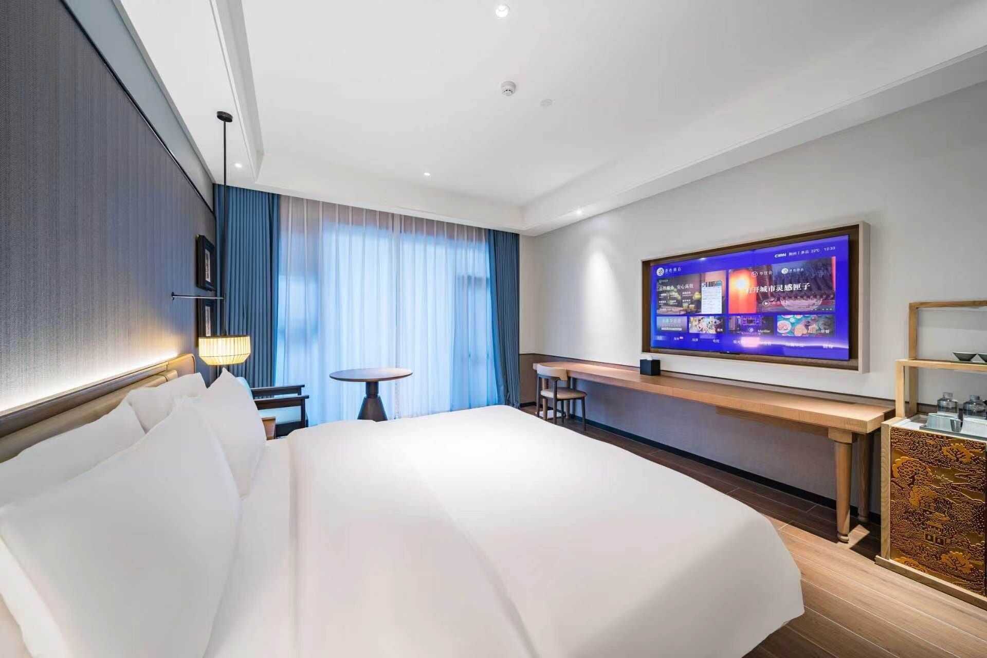 Habitación de hotel con una cama grande, un escritorio, un televisor y vistas a la ciudad.