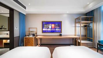 Habitación de hotel con cama, escritorio, televisor, armario y baño visible a través de una puerta abierta.