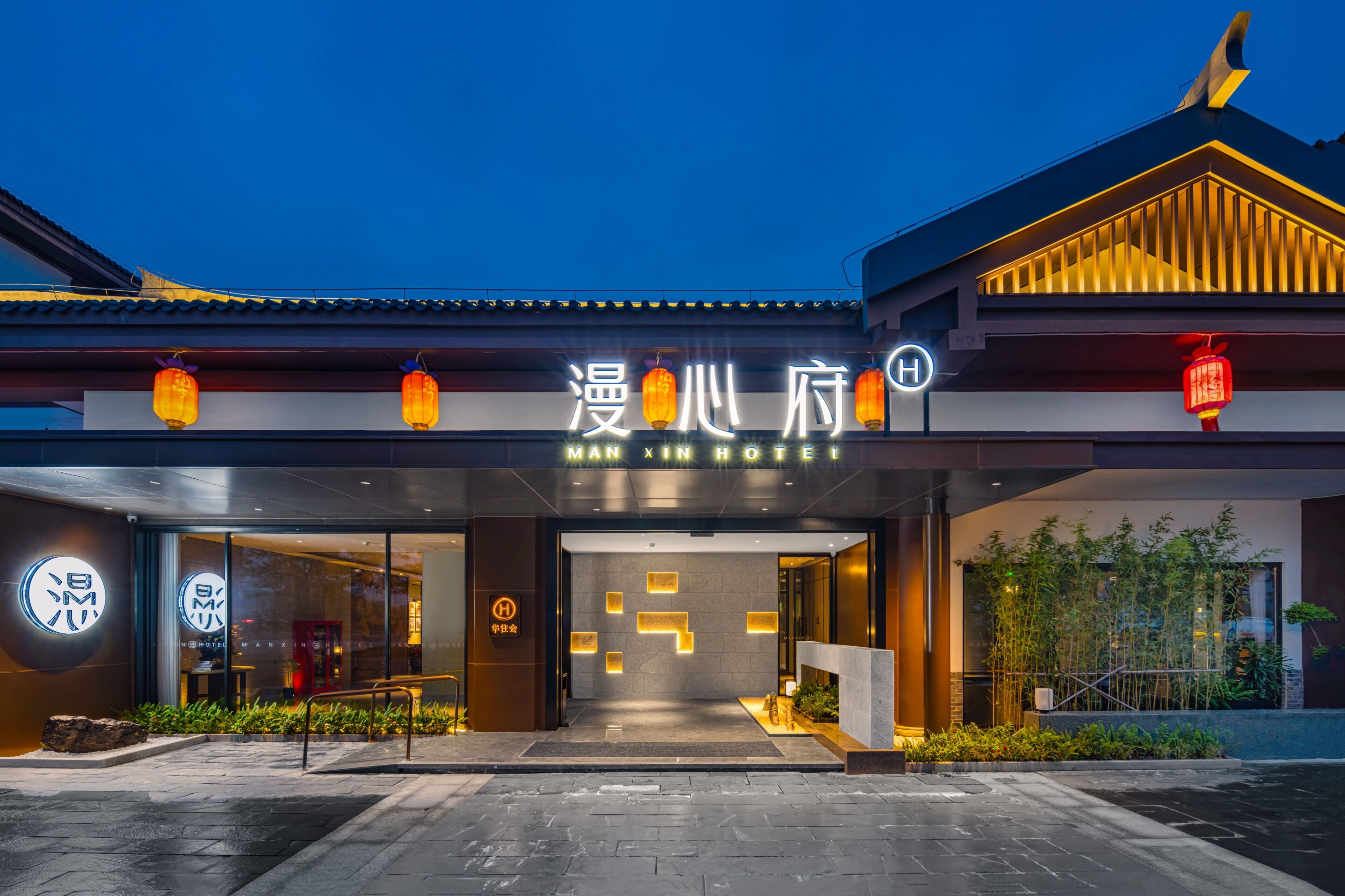 A hotel entrance with a traditional Chinese architectural style, featuring a modern glass facade and a signboard with the hotel's name.