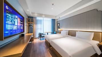 A hotel room with a large flat-screen TV, a desk, two beds, a small table, and a chair.