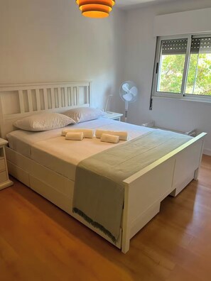 Quarto com cama, mesa de cabeceira e janela com vista.