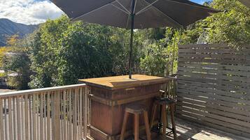An outdoor wooden deck with a barbecue area, a table, and a bench.