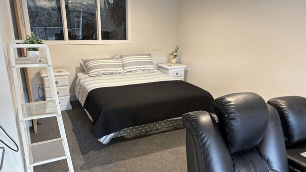 Un dormitorio con cama, mesita de noche, cómoda, silla y ventana.