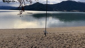 Una playa con un columpio y un lago tranquilo al fondo.