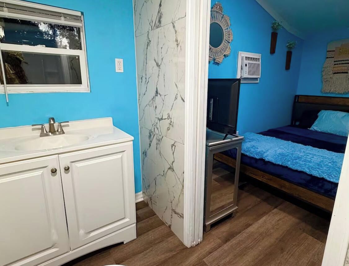 Une chambre à coucher avec un lit, une table de chevet, un miroir et une fenêtre.