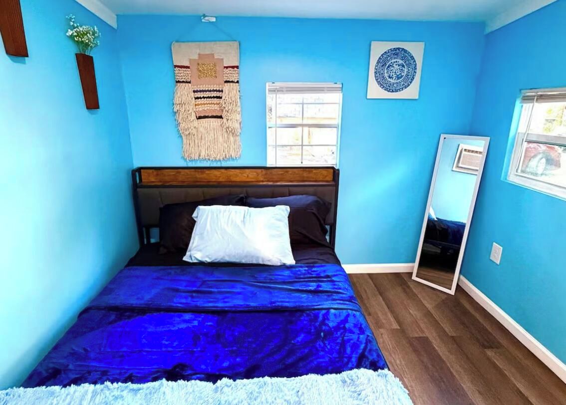 Une chambre à coucher avec un lit, un miroir, une fenêtre et des éléments décoratifs sur les murs.