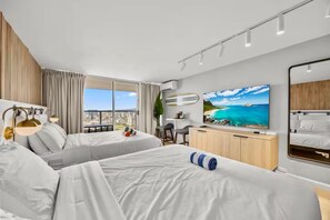 Ein Hotelzimmer mit zwei Betten, einem Fernseher, einem Balkon und Blick auf die Stadt.