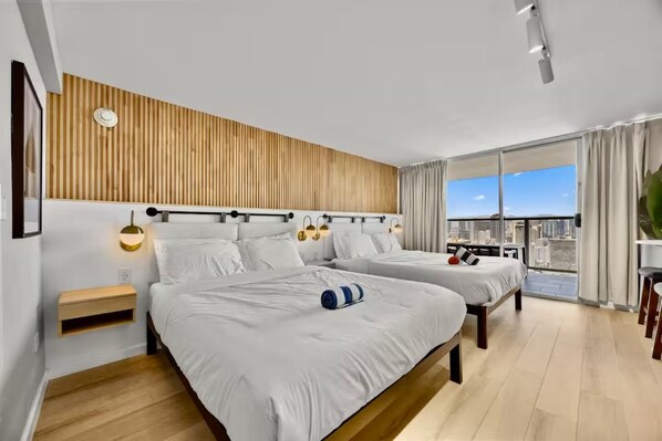 Ein modernes Hotelzimmer mit zwei Betten, einer Wand aus Holzlatten, einem Balkon mit Blick auf die Stadt und einem kleinen Tisch mit Stühlen.