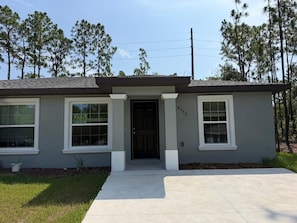 A single-story house with a dark front door, two windows on the left, and a mailbox.