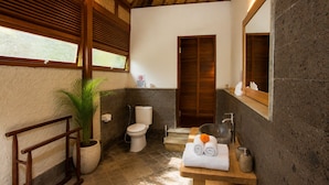 A bathroom with a wooden ceiling, a toilet, a sink with a basin, and a mirror. - Ubud Family Cabin Villa Riverside Bima (Gianyar)