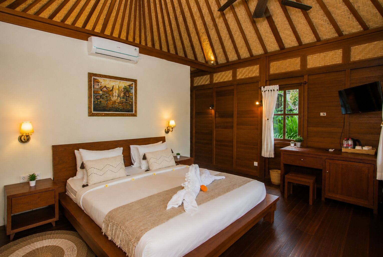Habitación de hotel con una cama grande, techo de madera, un cuadro en la pared, un escritorio con una silla y un televisor.