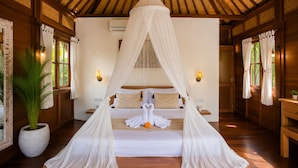 A room with a bed under a canopy, wooden walls, a potted plant, and wall-mounted lights. - Ubud Family Cabin Villa Riverside Bima (Gianyar)