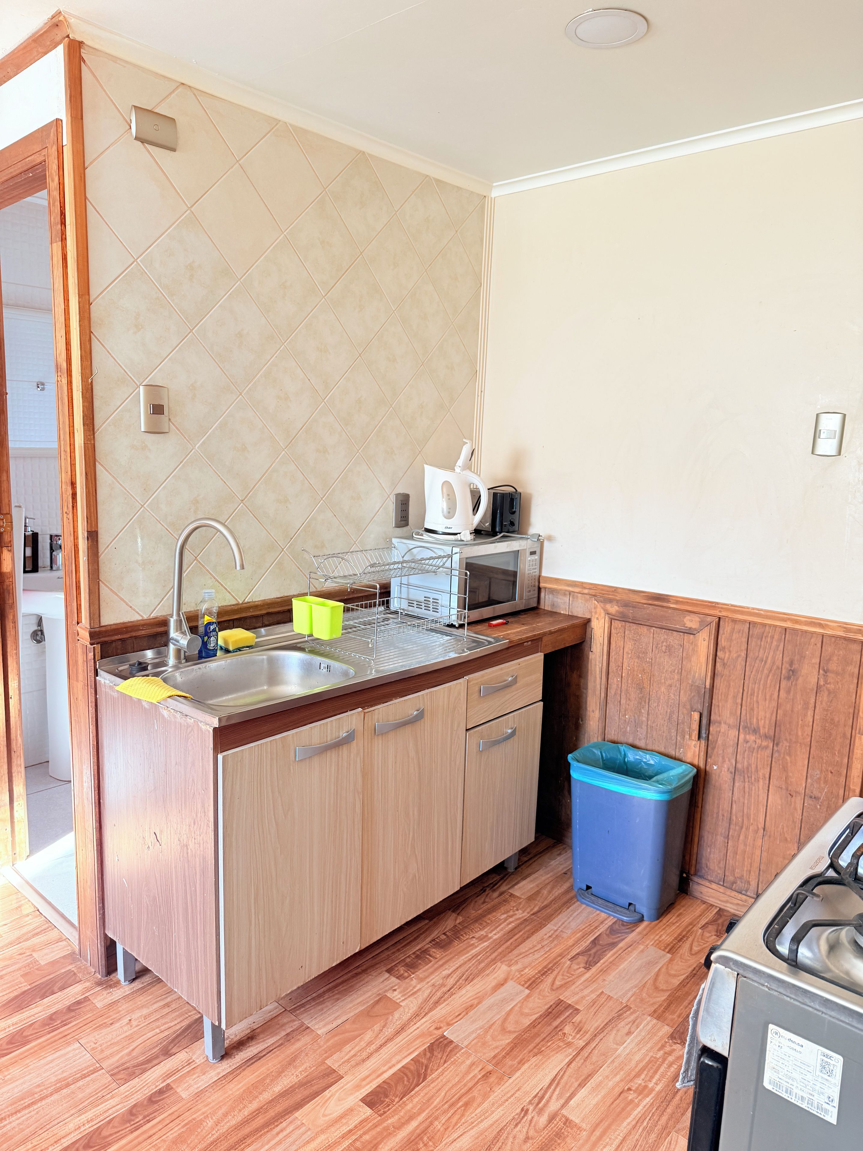 Une cuisine dotée d’un plan de travail en bois, d’un évier en acier inoxydable et d’un four à micro-ondes.