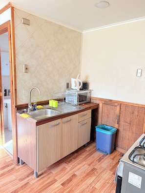 A kitchen with a wooden countertop, stainless steel sink, and a microwave.