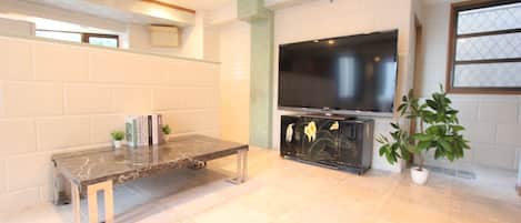 Una sala de estar con un televisor de pantalla plana, una mesa de centro de mármol y una estantería.