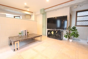 A living room with a flat-screen TV, a marble coffee table, and a bookshelf. - Spacious Private Stay Near Higashi-Shinjuku | Sleeps 10 | Families & Groups | WiFi (2) (新宿区新宿７丁目)