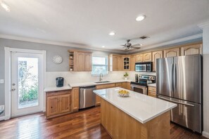 A modern kitchen with wooden cabinets, stainless steel appliances, and a central island. - Waterfront Marco Retreat: Pool, Dock, Game Room + Beach Gear (Marco Island)