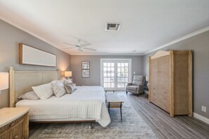 A bedroom with a bed, bedside tables, a chair, a wardrobe, and a ceiling fan. - Waterfront Marco Retreat: Pool, Dock, Game Room + Beach Gear (Marco Island)