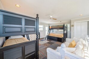 A bedroom with a bunk bed, a white sofa, and a ceiling fan. - Waterfront Marco Retreat: Pool, Dock, Game Room + Beach Gear (Marco Island)