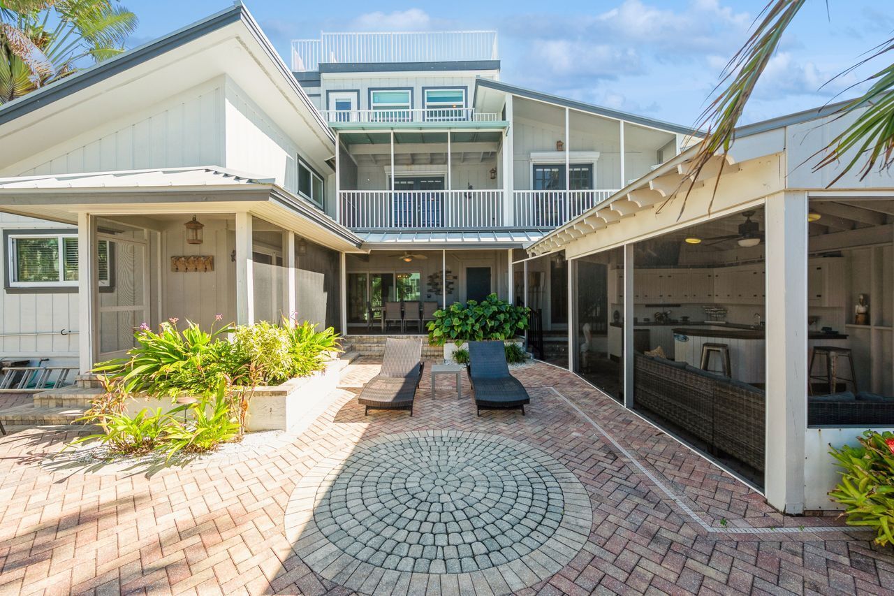 A modern house with a covered patio, outdoor seating, and a circular brick pattern.