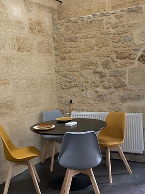 Ein Essbereich mit Steinwand, Tisch und Stühlen sowie einer Stehlampe.