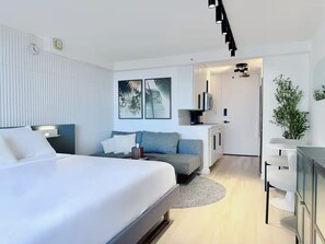Ein modernes Hotelzimmer mit einem großen Bett, einer Couch, einem Schreibtisch und einem Fernseher.