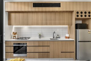 A modern kitchen with wooden cabinets, a stainless steel refrigerator, and a built-in dishwasher.