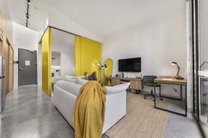 A modern living room with a sofa, a desk, and a television. - No 5 Coppin in Yellow and Black (Richmond)