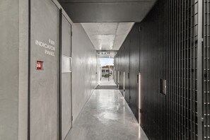 A corridor with a fire indicator panel on the left and a metal security gate on the right.