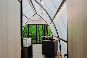 Une tente équipée d’un coin cuisine, d’un barbecue et d’un espace détente offrant une vue sur une forêt.