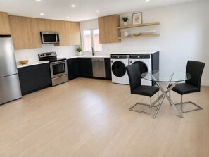 Una cocina moderna con electrodomésticos integrados, un comedor con mesa de vidrio y una lavadora.