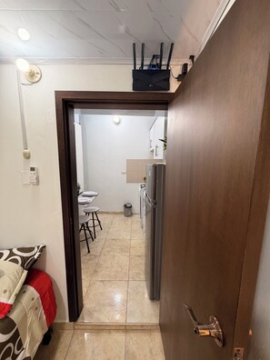 Un pasillo estrecho que conduce a una cocina con refrigerador y comedor.