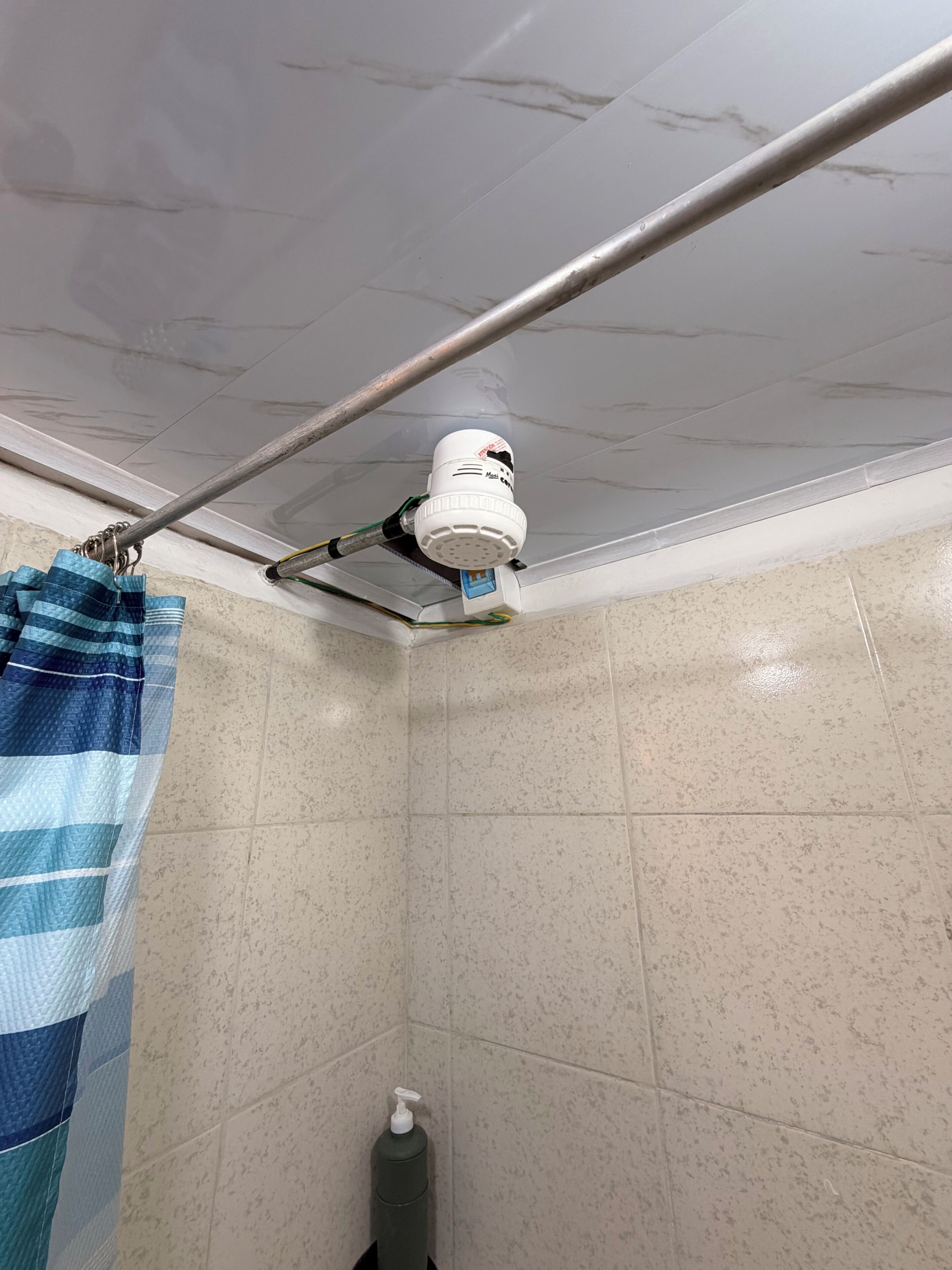 Bany amb cortina de dutxa, plat de dutxa manual i dosificador de sabó.