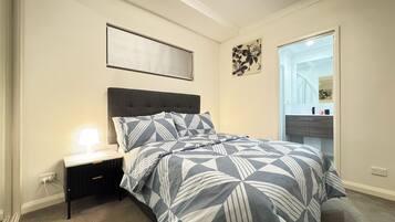A bedroom with a bed, bedside table, and a nightstand.
