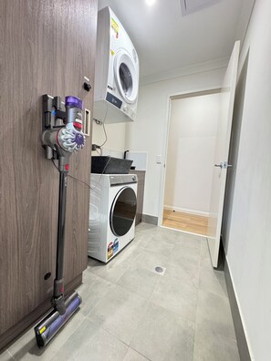 A laundry area with a washing machine, a dryer, and a vacuum cleaner.