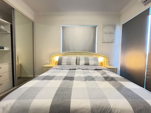 Een slaapkamer met een bed, nachtkastjes, een kledingkast en een raam.