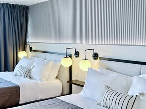 Ein Hotelzimmer mit zwei Betten, einem Kopfteil und Wandleuchten.