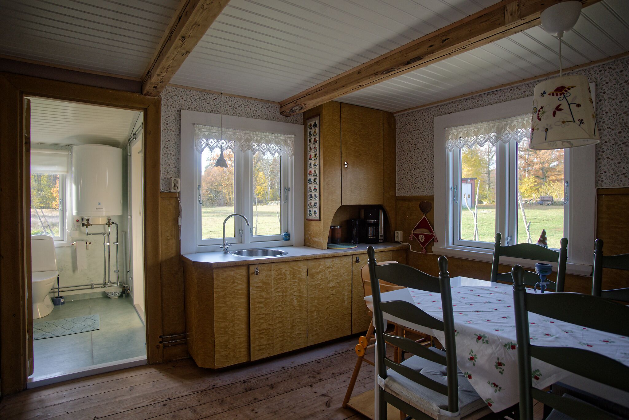 Une cuisine chaleureuse, aménagée dans le style d’un chalet, avec un intérieur en bois, un évier et un coin repas comprenant une table et des chaises.